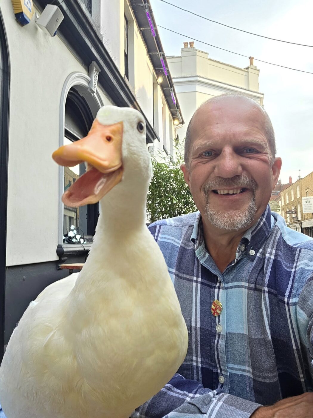 Mark grinning with Goldie the duck close to camera, on a Rochester street
